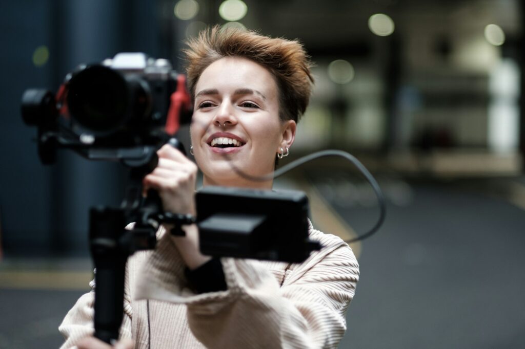 A young woman videographer is recording some video outdoors.