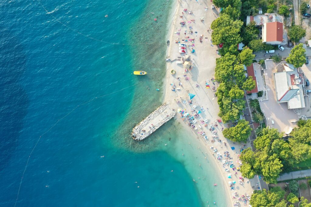 Aerial shot of a beat on the water near the shore with building st daytime in Makarska, Croatia